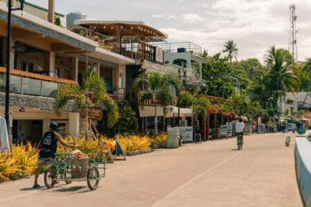 Everyday street scene in Puerto Galera, Philippines with locals going about their daily routines, capturing the relaxed rhythm of life beyond the tourist highlights