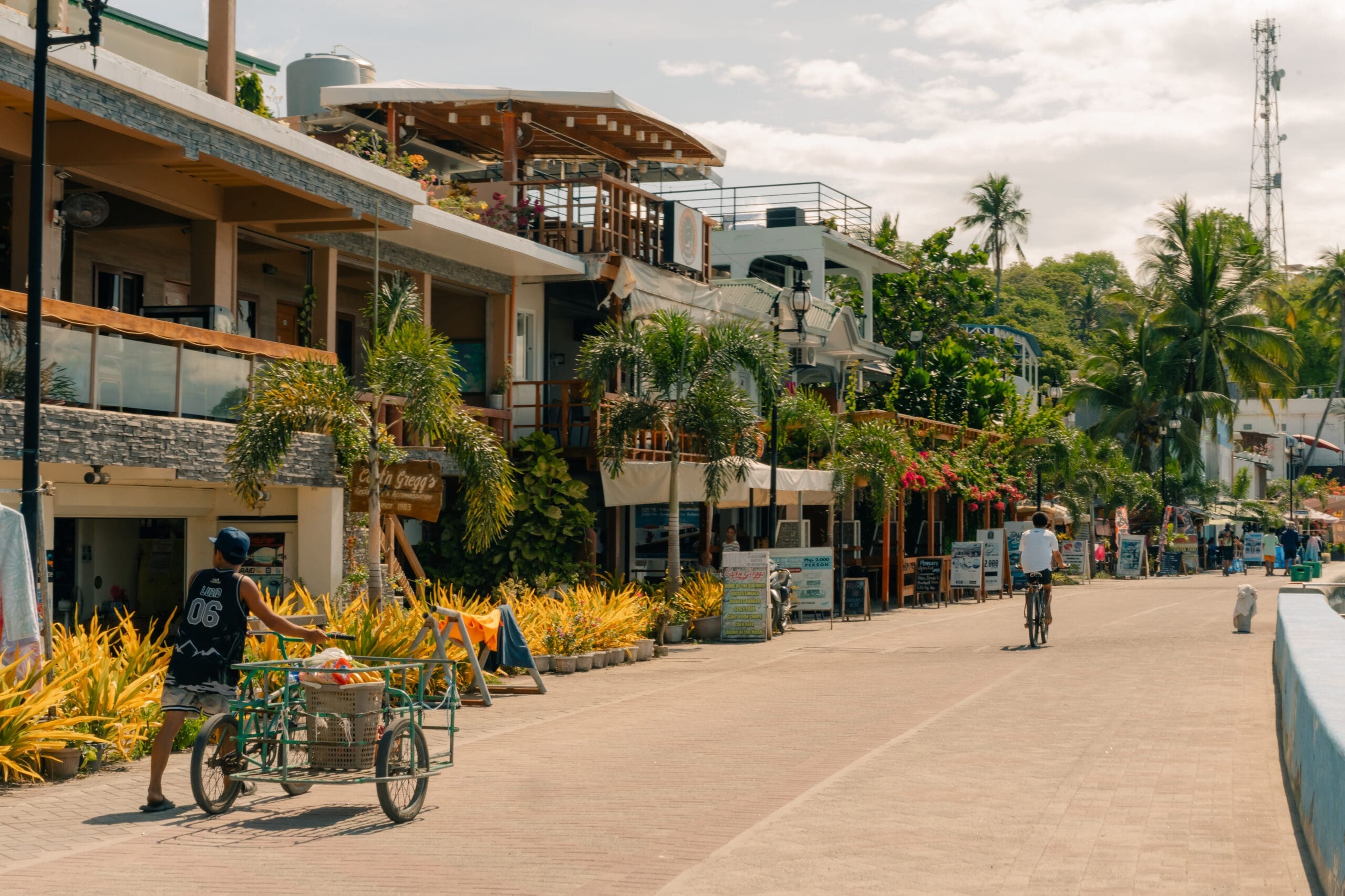 Everyday street scene in Puerto Galera, Philippines with locals going about their daily routines, capturing the relaxed rhythm of life beyond the tourist highlights